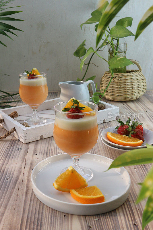 orange pudding in a glass garnished with sliced ​​oranges and strawberries